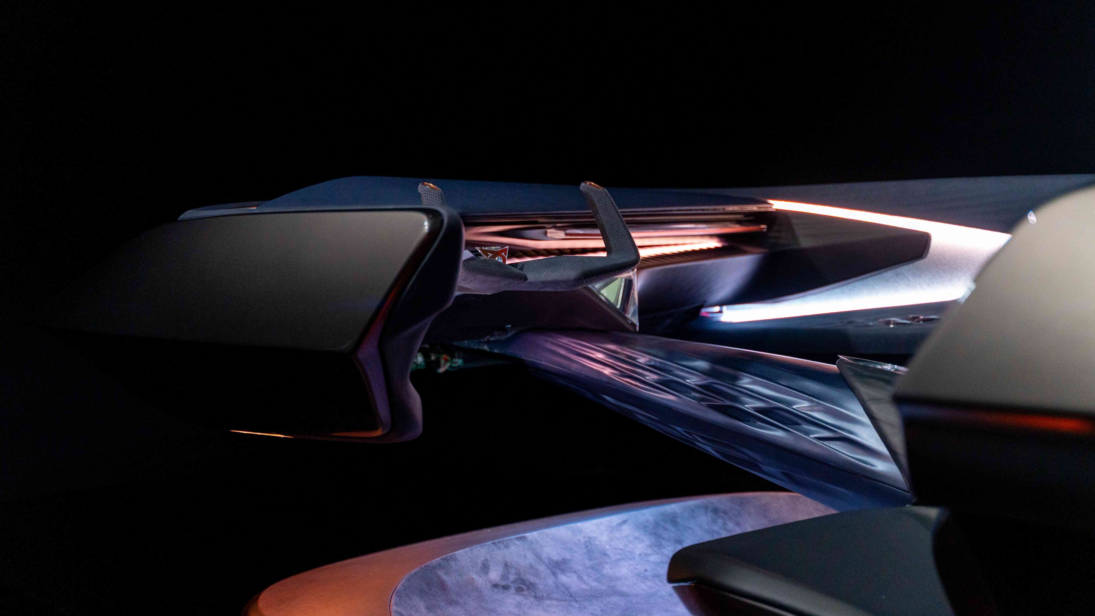 Prikaz futurističnega leteča vozila v temnem okolju z osvetljenimi podrobnostmi. Naprava ima aerodinamične poteze in zapleteno strukturo. Osvetlitev poudarja oblikovne značilnosti naprave.